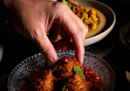 hand picking up savoury donut from plate